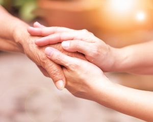 Caregiver, carer hand holding elder hand in hospice care. Philanthropy kindness to disabled concept.
